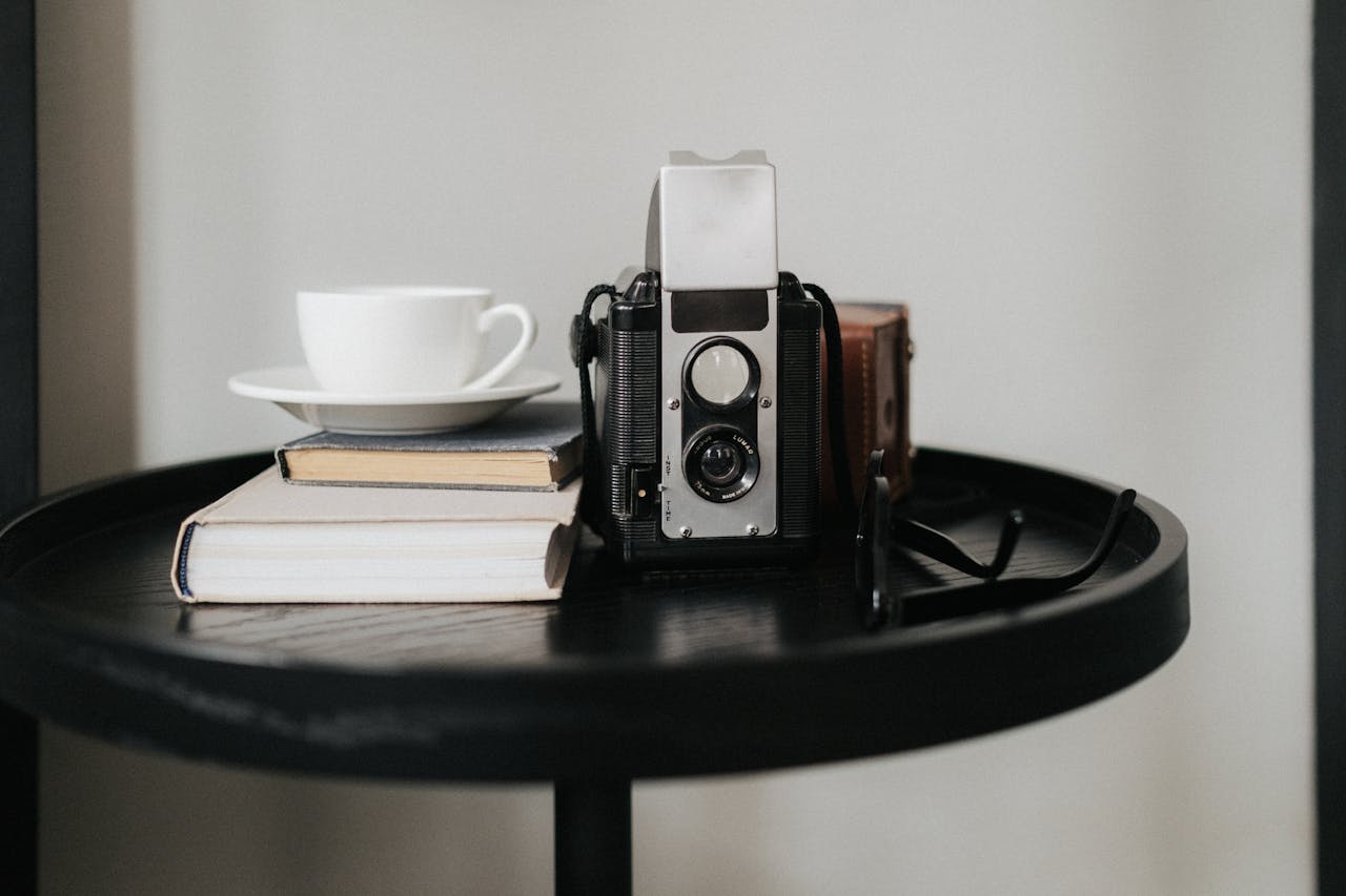 A vintage camera sits alongside books and a cup on a stylish indoor table.